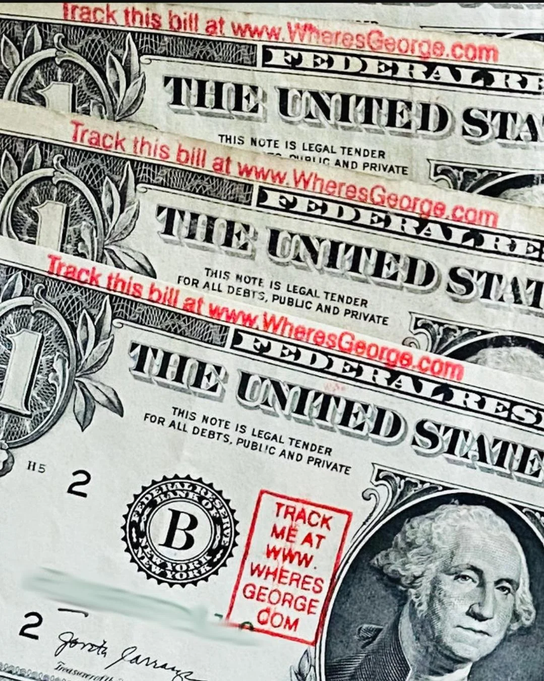 United States dollar bills stamped with Where’s George? promotions in red ink