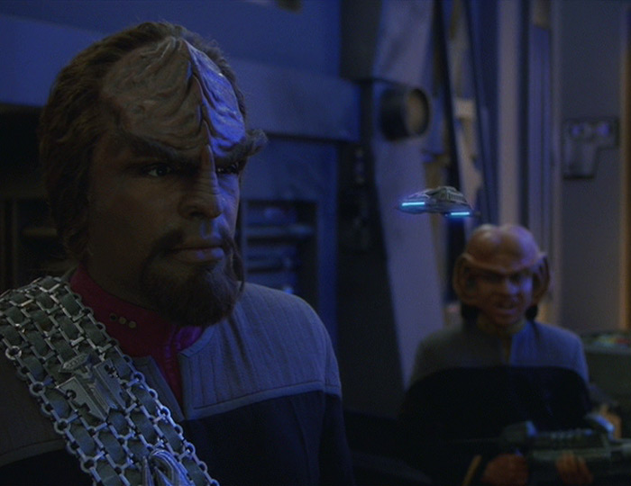 A screenshot from "One Little Ship", showing Worf staring at a runabout that has shrunk to the size of a small toy.